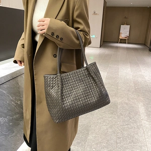 Classic dark grey woven leather tote bag shown in a luxury indoor setting with a model