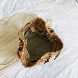 Interior detail of woven straw bucket bag showing drawstring closure and inner zip pocket