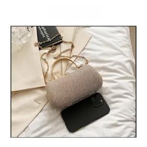 Champagne gold evening clutch with metal handle shown next to smartphone for size comparison