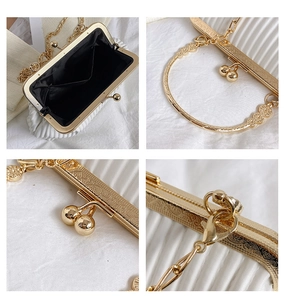 Macro detail of white pleated evening bag with vintage gold engraved metal frame and clasp