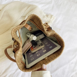 Spacious woven bucket bag interior showing daily items and leather drawstring detail