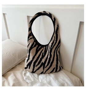 Dettaglio della borsa in maglia con motivo zebra nero e beige su superficie in tessuto