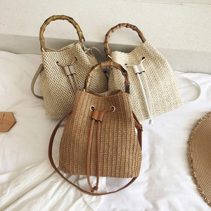 Close-up of woven bucket bags with natural bamboo handles and drawstring closure