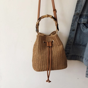 Close-up of woven straw bucket bag featuring retro bamboo handles and drawstring closure