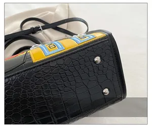 Détail du sac noir à motif crocodile avec broderies et clous de fond en métal