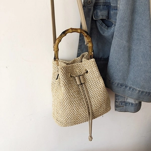 Detail of woven straw bucket bag showing bamboo handle and drawstring closure