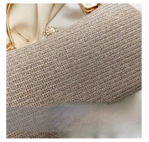 Close-up of champagne glitter evening clutch with diamond-studded clasp and metal handle