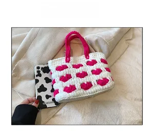 Borsa a mano all'uncinetto rosa e bianca a onde con confronto dimensioni con telefono