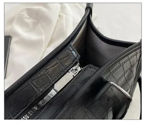 Détail de la fermeture éclair argentée et texture crocodile sur le sac noir