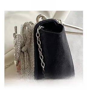 Detail of velvet evening bag featuring silver metal chain and sparkling crystal bow accent