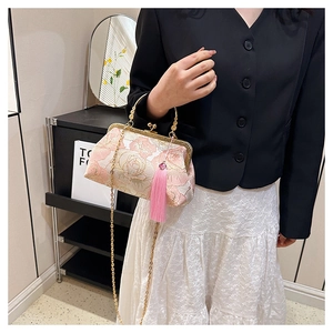 Détail du sac bandoulière vintage à fleurs avec poignée dorée et long pompon rose