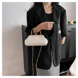 Detail of white pleated evening clutch featuring golden metal handle and fine chain strap