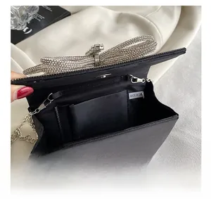 Macro view of black evening bag interior with metal chain and rhinestone bow detail
