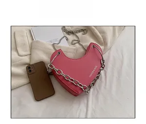 Sac à bandoulière rose en forme de cœur avec chaînes argentées et comparatif de taille