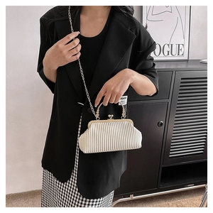 Close-up of white pleated texture evening bag with gold handle and clasp detail