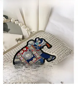 Close-up of pearl handle and colorful elephant embroidery on rhinestone evening bag