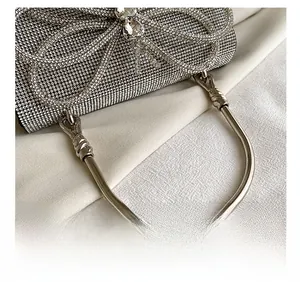 Detail of silver rhinestone evening bag featuring a crystal bow and metallic round handle