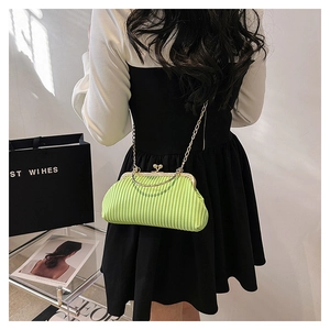 Detail of neon green pleated frame bag with vintage metal clasp and gold chain strap