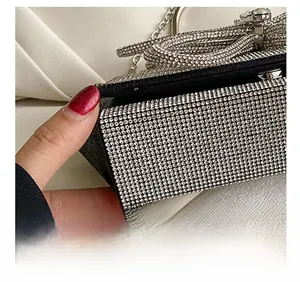 Detailed macro view of the black evening bag featuring a sparkling rhinestone bow buckle