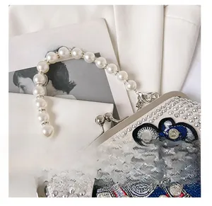 Detail of luxury evening bag with lion embroidery and large pearl handle strap