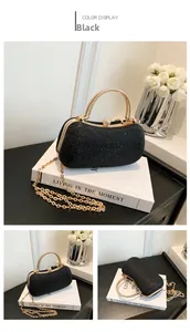 Detail view of black sequined evening bag with golden metal handle and crystal clasp