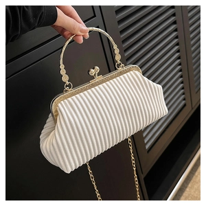 Detail of white pleated fabric evening clutch with golden engraved frame and pearl clasp