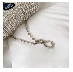 Close-up of diamond-studded handbag with blue butterfly embroidery and metal ball chain
