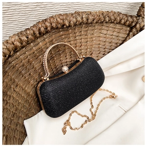Detail of black glitter evening clutch with pearl clasp and diamond-encrusted gold handle