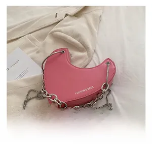 Détail d'un sac rose en forme de cœur avec des chaînes argentées et un logo imprimé