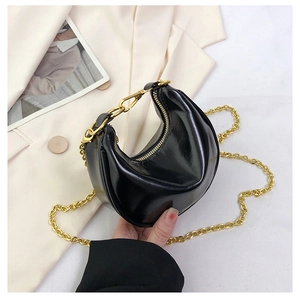 Close-up of black glossy crescent bag with chunky gold chain strap and zipper