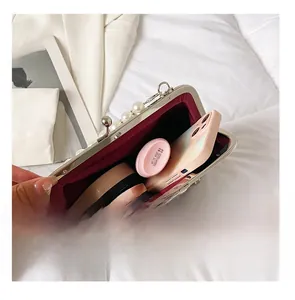 Detail view of pearl-beaded evening clutch interior with phone and lipstick
