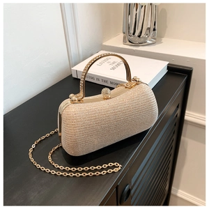 Close-up of champagne gold glitter evening bag with crystal lock and diamond handle