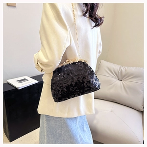 Detailed view of black sequined clutch bag with gold metal frame and chain strap
