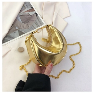 Detail of metallic gold crescent bag with glossy finish and delicate chain strap