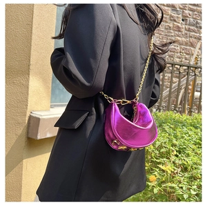 Detailed close-up of metallic purple crescent bag with golden chain and letter charms