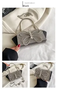 Detail of black evening clutch bag with large rhinestone butterfly and metal handle