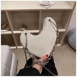 Détail d'un sac cœur crème en similicuir avec chaîne argentée et logo imprimé fashion