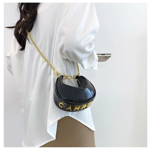Detail of black crescent shoulder bag with golden chain and metallic logo on white shirt