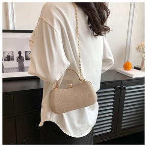 Golden glitter evening bag with metallic handle and chain strap worn by model