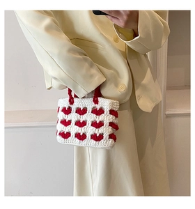 Dettaglio della mini borsa a mano all'uncinetto con cuori rossi su maglia bianca