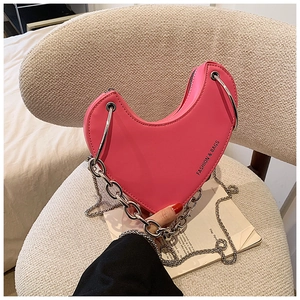 Vue détaillée du sac coeur en cuir rose avec chaîne argentée et poignée en métal