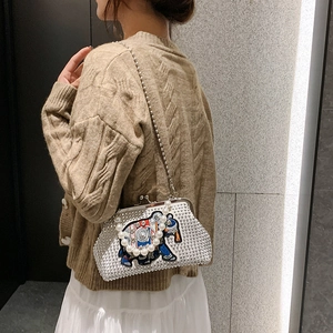 Detail view of rhinestone elephant clutch featuring white pearls and a luxury chain strap