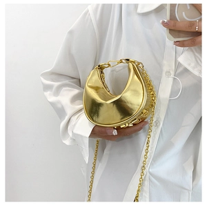 Close-up of golden crescent bag with metallic mirror finish and delicate chain strap