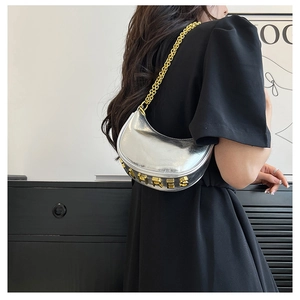 Detail of silver crescent bag with HRE S metal letters and golden chain shoulder straps