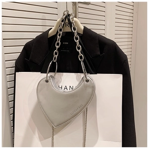 Détail du sac argenté en forme de cœur avec poignée anneau métal et logo mode