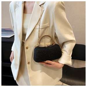 Close-up of black glitter evening clutch with gold metal frame and spherical clasp
