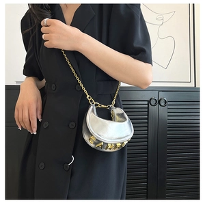 Detail of silver crescent bag with gold chain strap and metallic letters on model
