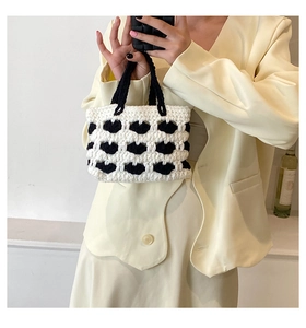 Dettaglio della mini borsa all'uncinetto fatta a mano con motivi di labbra nere su maglia bianca