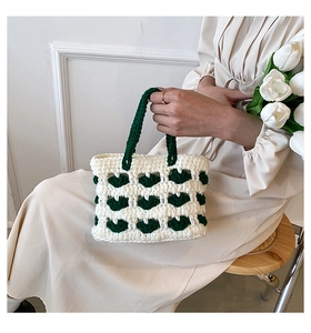 Dettaglio della borsa all'uncinetto con maglia beige e motivo a cuore verde