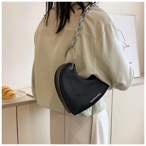 Détail d'un sac cœur avec poignée en métal argenté et bandoulière en chaîne métallique
